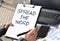 Business girl works at the table outdoors. The girl is holding a tablet for papers with the inscription SPREAD THE WORD.