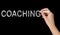 Business or life trainer writing word Coaching on blackboard