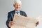 Business Lifestyle. Businessman standing isolated on gray reading newspaper happy close-up