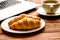 Business lunch with croissant and laptop on wooden desk