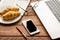 Business lunch with croissant and laptop on wooden desk