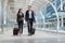 business man and business woman wear black suit walk together with luggage on the public street