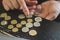 business man counting money. rich male hands holds and count coins of different euros on table in front of a laptop.