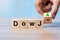Business man Hand change wood cube block with Dow J text to UP and Down arrow symbol icon. Interest rate, stocks, financial,