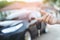 Business man hand holding car keys front with car on background.