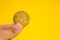 Business man hand holding Monerd coin between fingers on yellow background. Digital currency, block chain market, online business