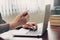 Business man hand texting laptop and holding phone on wooden table