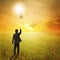 Business man holding bulb balloon in fields and sunset