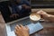 Business man holding coffee cup and typing on laptop computer keyboard on wooden table. Close up male hands with notebook pc