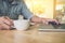 Business man holding a cup of coffee and using laptop, notpad on