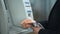 Business man inserting credit card in ATM, entering pin code to receive money