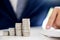 Business man putting coin to rising pile of money and calculator