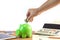 Business man putting money coin into green piggy bank, finance a