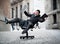 Business man rolling downhill on chair with computer and tablet