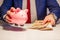 Business man showing in hand fifty euro banknote and holding piggy bank