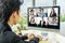 Business man sit at desk looking at computer screen where collage of diverse people webcam view. Asian man lead video call distant