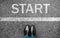 Business man standing on grunge concrete with white race line beginning idea. Top view. Feet and black shoes with word start