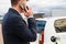 Business man standing near the charging electro and talking on the smartphone