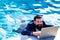 Business man in suit with laptop on swimming pool. Funny businessman relaxing with laptop.