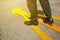 Business man in suit standing on floor with yellow arrow symbol. Top view. Selfie of feet in black leather shoes on street road