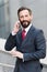 Business man talking active with the client on a cell phone out of office building. Handsome bearded manager outdoor makes call