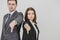 Business man and woman standing back to back, giving thumbs down, frowning. Focus on the gesture on the forefront.