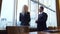 Business man and woman are standing by the panoramic window in their office