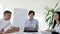 Business meeting of collaborators at desk with documents in hand in boardroom