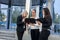 Business meeting outside building. Three young ladies in business suits discussing information on tablet