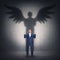 Business metaphor with a person casting a hero shadow on the wall. Powerful superhero or guardian angel with wings. Inner strength