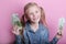 Business and money concept - happy little girl with euro cash money over pink background