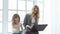 Business mother with laptop and daughter sitting by the window