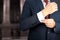 Business and office concept - elegant young fashion buisness man in a blue/navy suit touching at his cufflinks