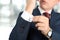 Business and office concept - elegant young fashion buisness man in a blue/navy suit touching at his cufflinks