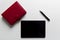 Business office items on white table, tablet and red notebook wi