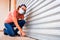 A business owner closes her business definitively by lowering the metal blind due to the economic crisis