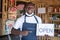 Business owner wearing a face mask and holding an open sign in front of his shop and smiling