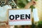 Business owner woman in apron showing welcome sign