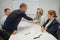 Business partners shake hands. Four business people are negotiating in the conference room.