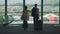 Business partners walking to airport escalator, carrying luggage, tourism