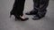 Business people flirting standing outdoors. Woman flirt with man. Man and woman feet in black clothes with woman lifting