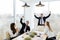 Business people in formalwear celebrate victory while sitting together at the table