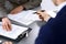 Business people and lawyer discussing contract papers sitting at the table, hands close-up. Teamwork or group operations