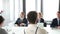 Business people sitting at table while female colleague giving presentation