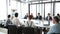 Business people sitting at table while female colleague giving presentation