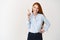 Business people. Young lady with ginger hair wearing blue shirt and pointing finger up, smiling as giving recommendation