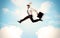 Business person jumping over clouds in the sky