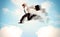 Business person jumping over clouds in the sky