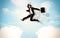 Business person jumping over clouds in the sky