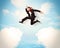 Business person jumping over clouds in the sky